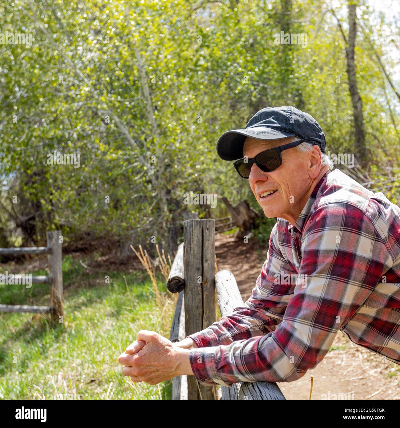 Senior farmer leaning on wooden fence near Sun Valley Stock Photo