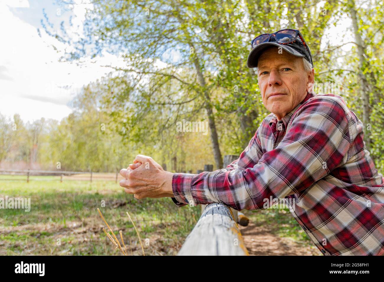 Portrait of senior farmer leaning on wooden fence near Sun Valley Stock Photo
