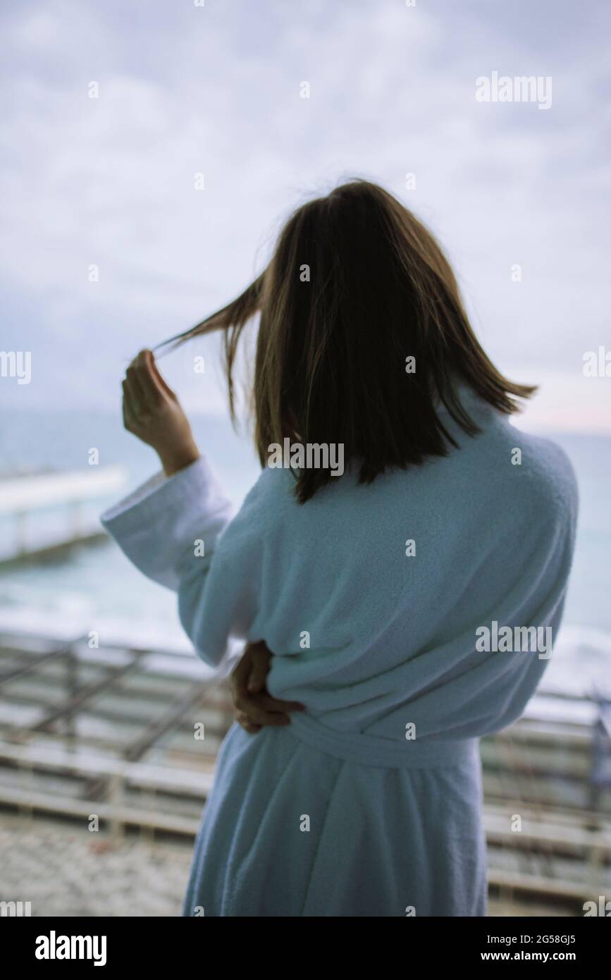 Rear view of woman in bathrobe in hotel with view on sea Stock Photo