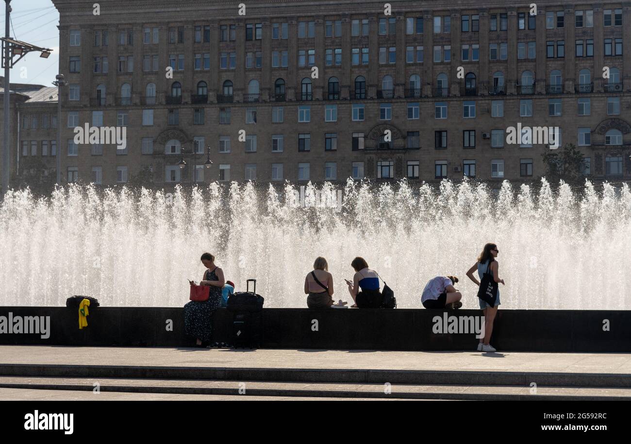 People refresh by city sprinkling water fountain on a hot summer day during heatwave, Moskovskaya sq, St Petersburg, Russia Stock Photo