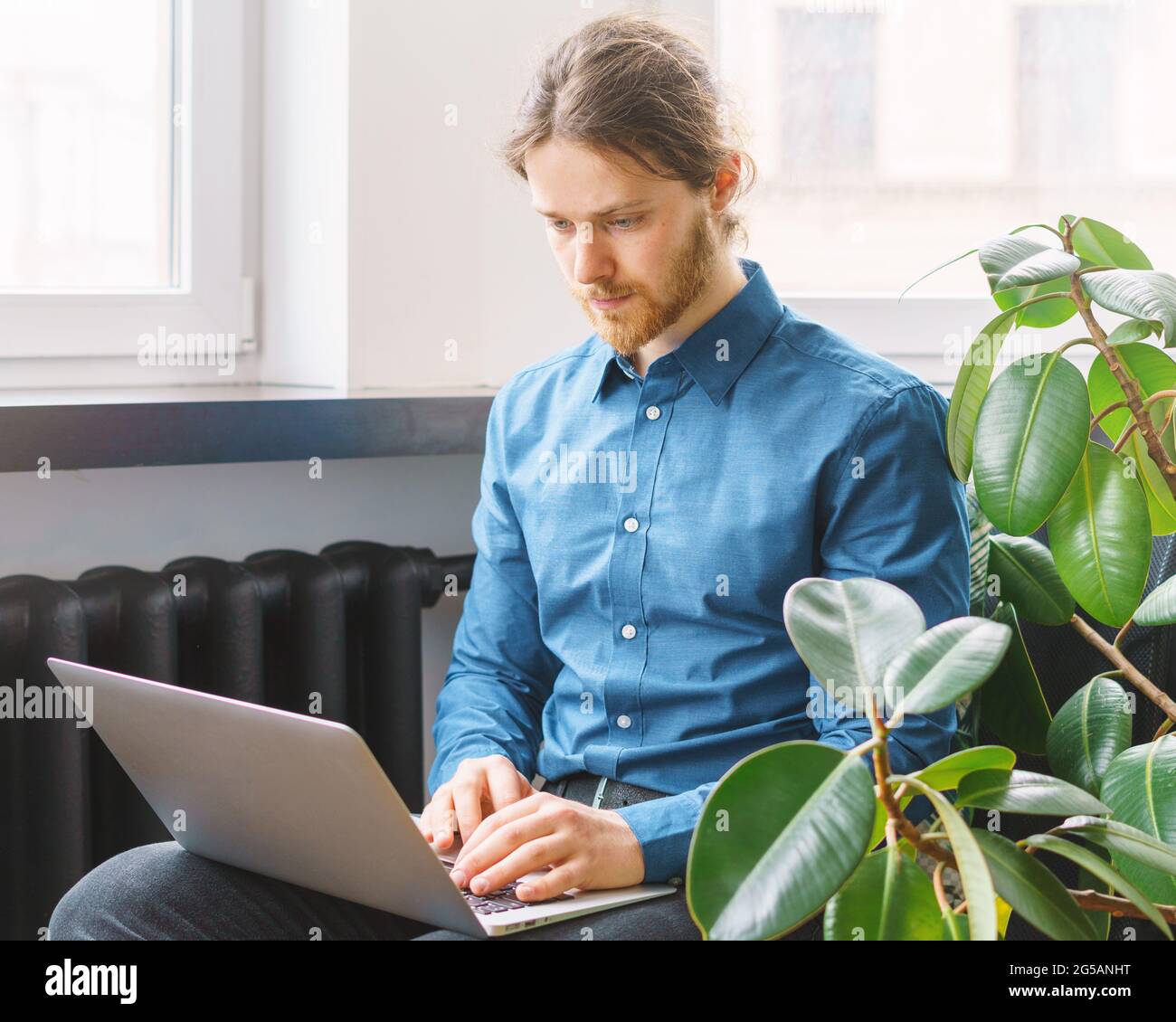 Focused young man in formal outfit working on laptop in office Stock Photo