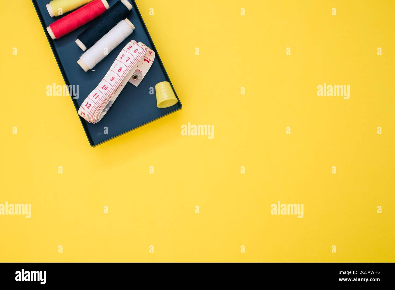 Pack of colorful sewing threads and a measuring tape on yellow ...