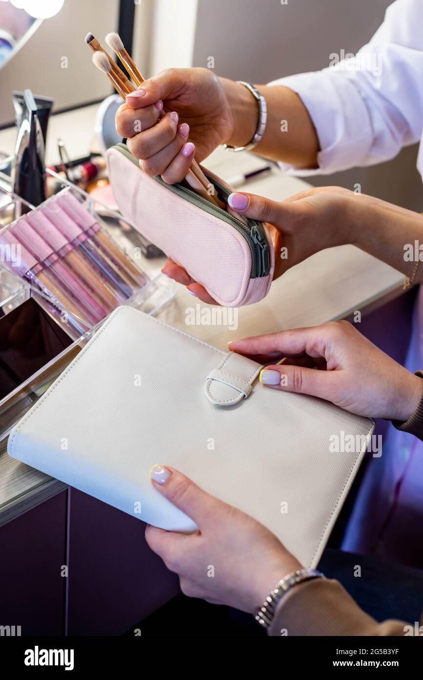 Female makeup artist parsing cosmetic bag of client. Teaching choosing