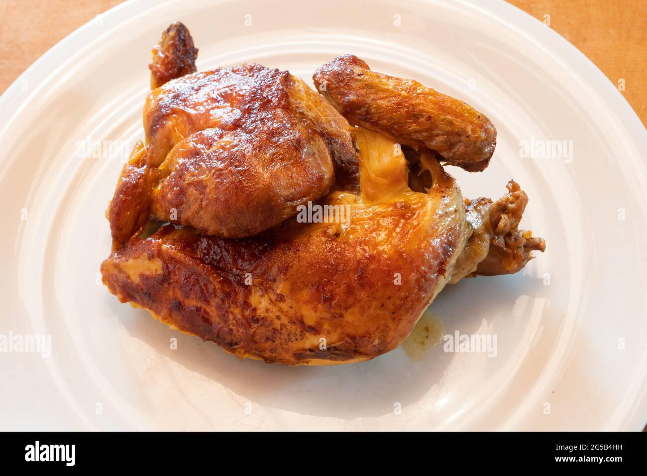 Roast Chicken Half on a White Plate, Rotisserie Chicken with Crispy Brown Skin Stock Photo