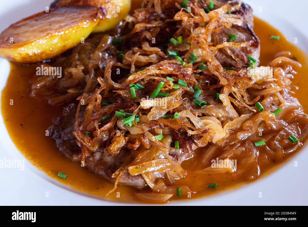 Viennese Zwiebelrostbraten, Sirloin Roast Beef with Onion Gravy, Crispy Fried Onion and Roasted Potatoes Close Up Stock Photo