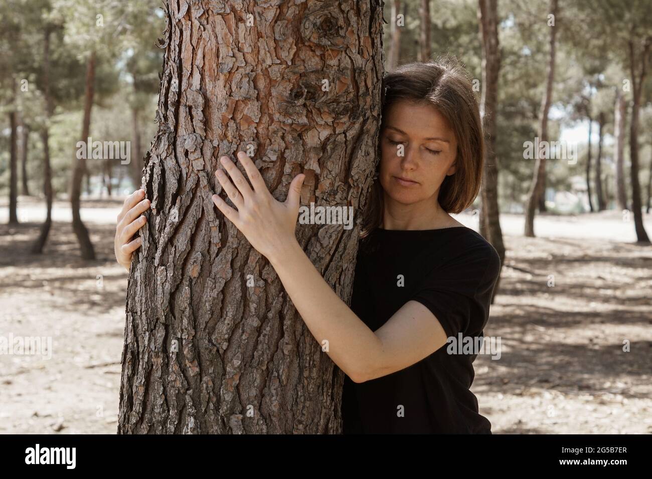 Middle-aged sensual Caucasian woman hugging a tree and loving nature at ...