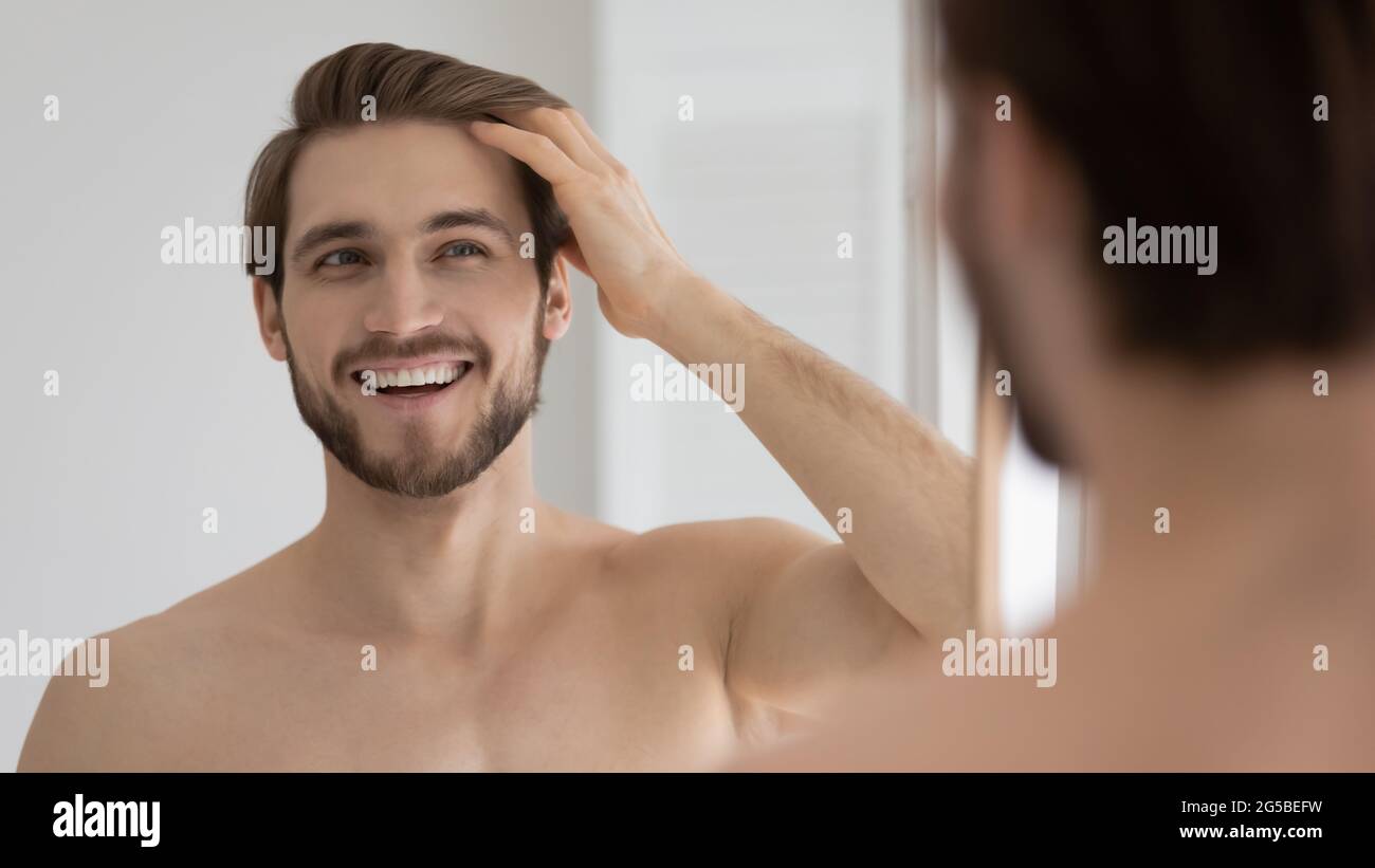 Happy handsome young guy combing smooth brown hair with fingers Stock Photo