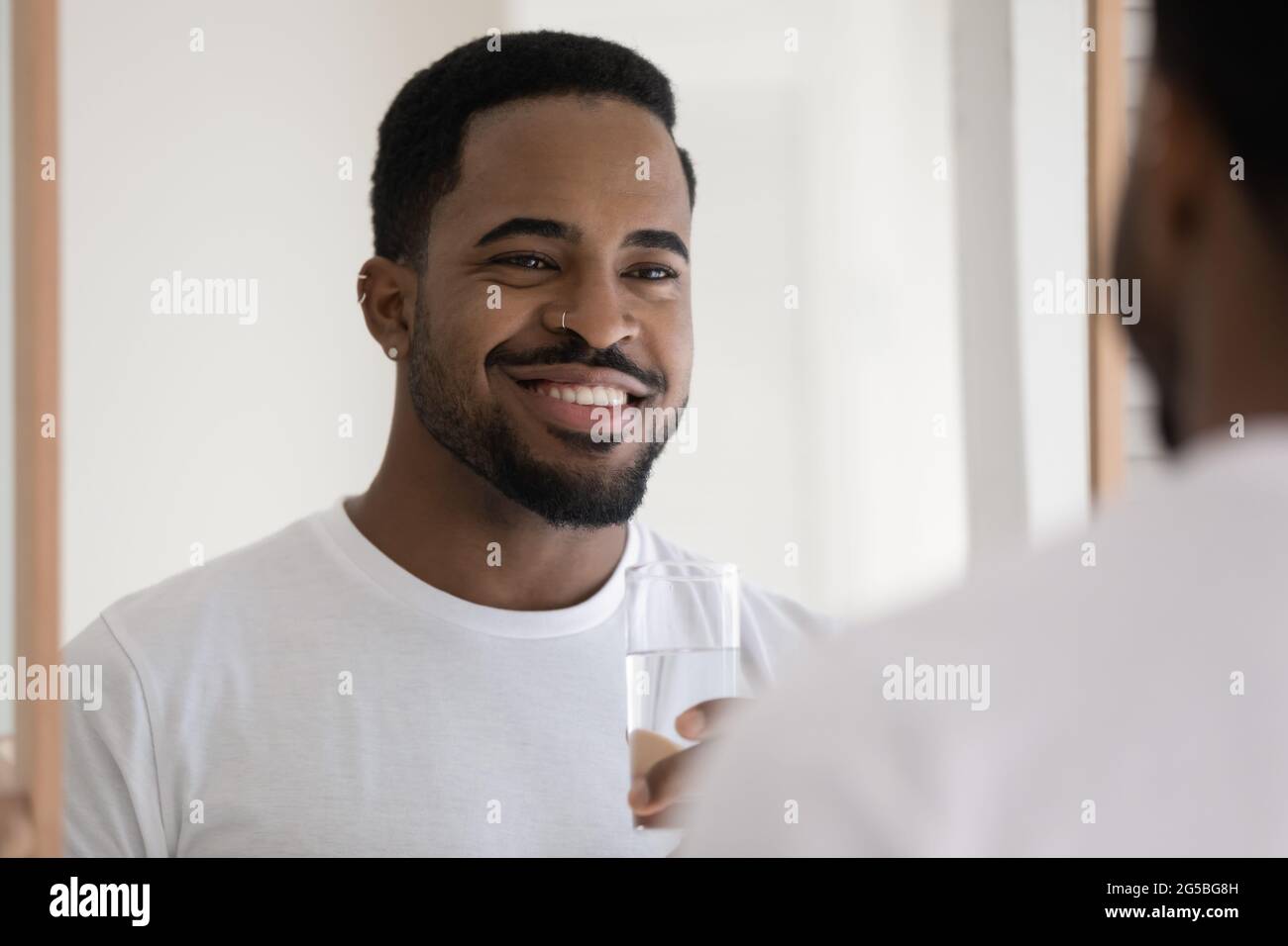 Happy handsome stylish mixed race Black guy drinking pure water Stock Photo
