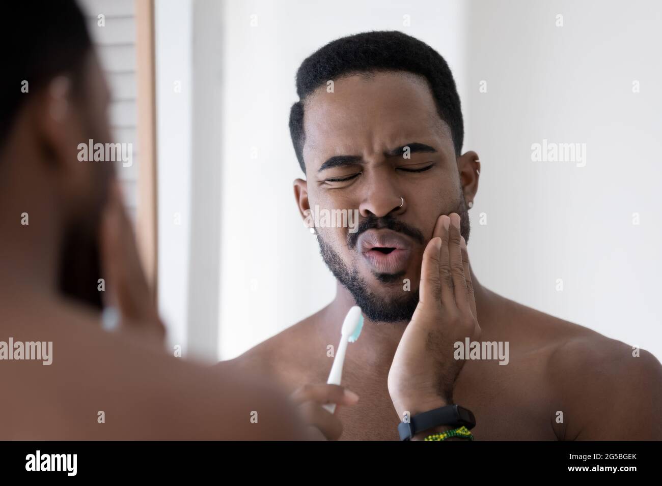 Stressed upset mixed raced Black man feeling pain and discomfort Stock Photo