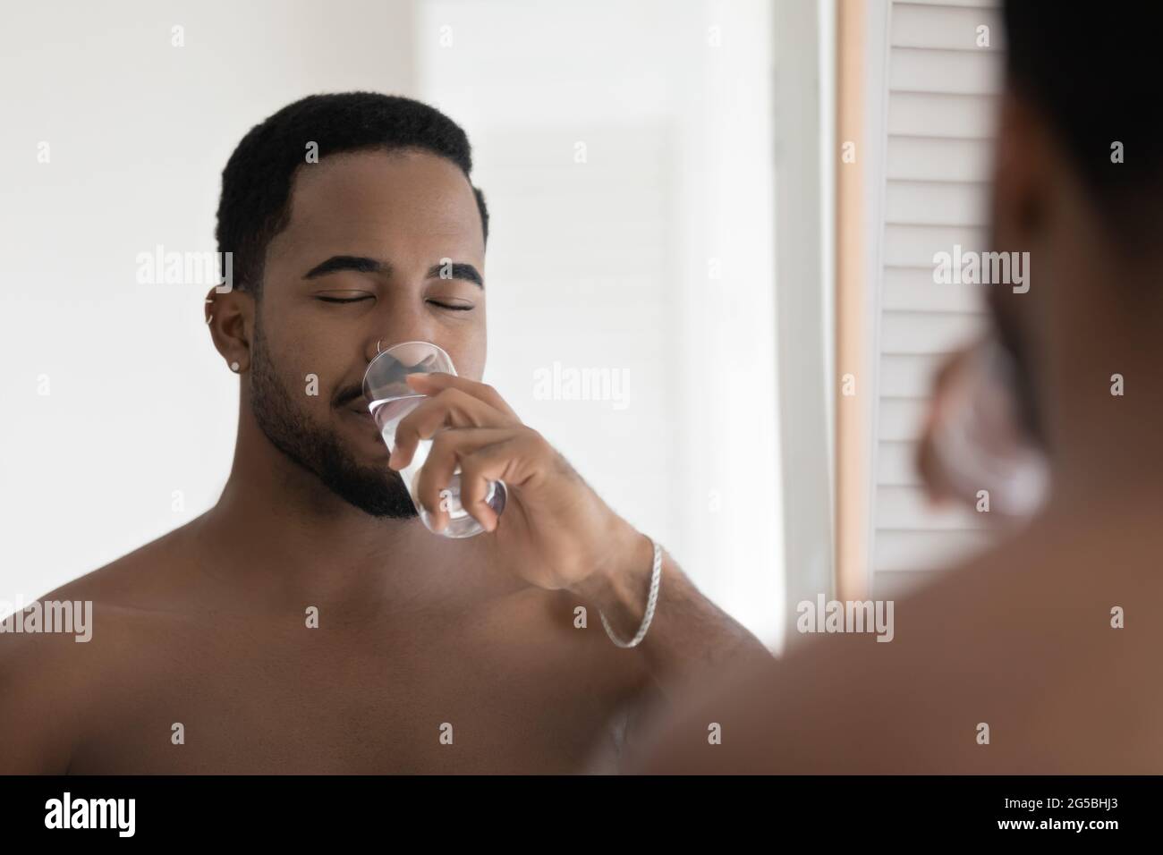 Happy relaxed handsome athletic Black guy drinking pure filtered water Stock Photo