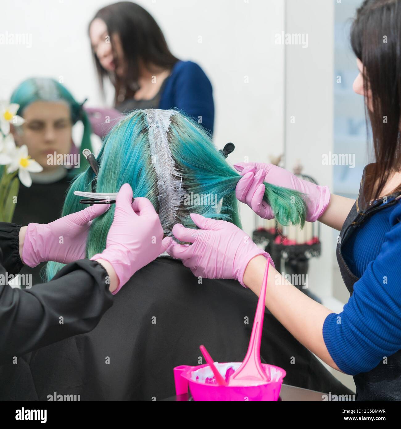 Process of hair dyeing in beauty salon. Two female hairdressers in pink