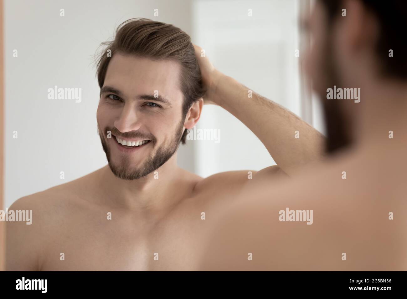 Happy attractive young guy touching smooth silky hair Stock Photo