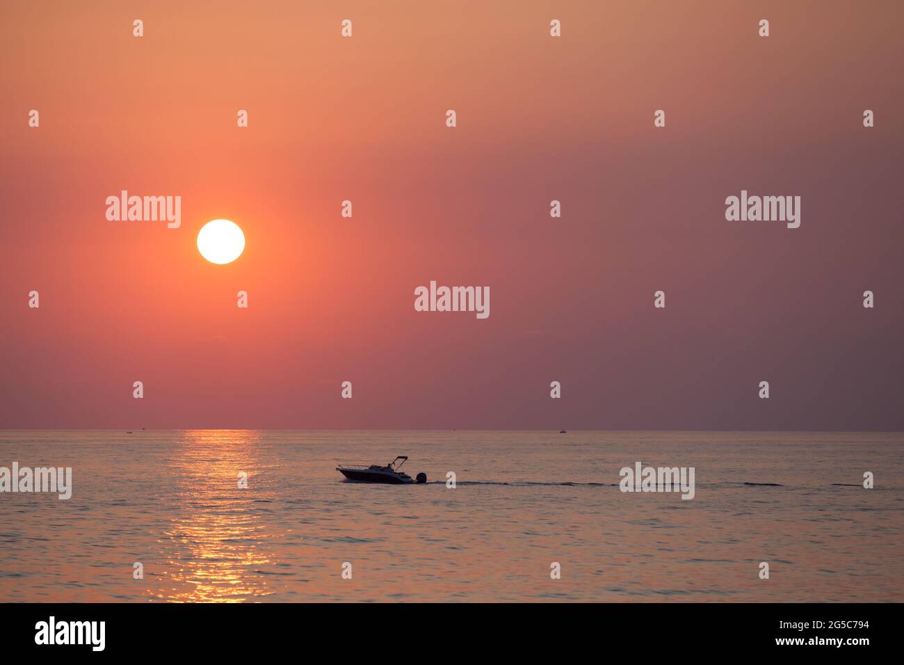 Sunset seascape with a silhouette of a pleasure motor boat sailing near Valletta, Malta Stock Photo