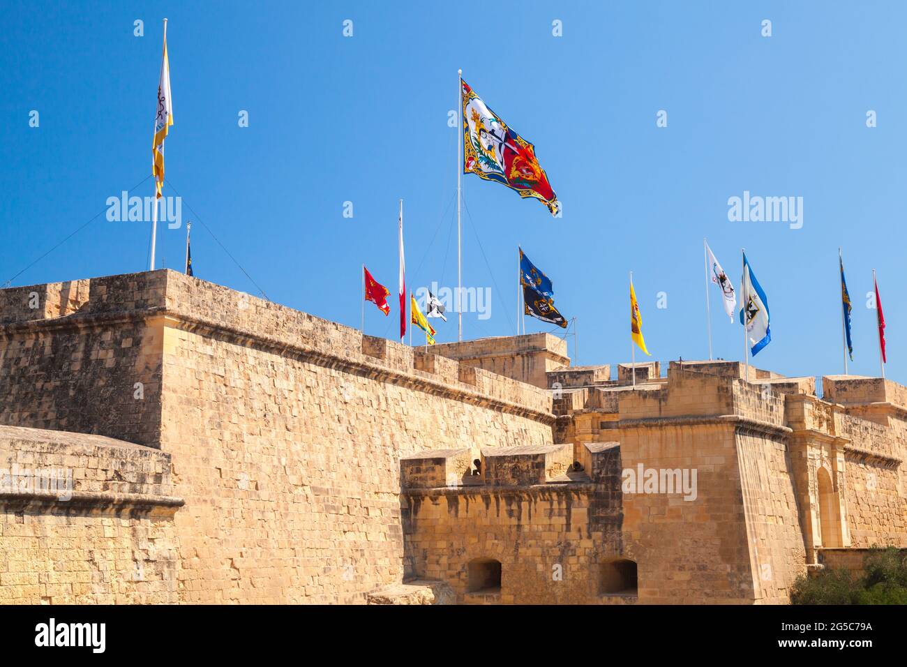 Colorful flags are on walls of the Armoury of the Knights of Malta. Birgu, Malta Stock Photo