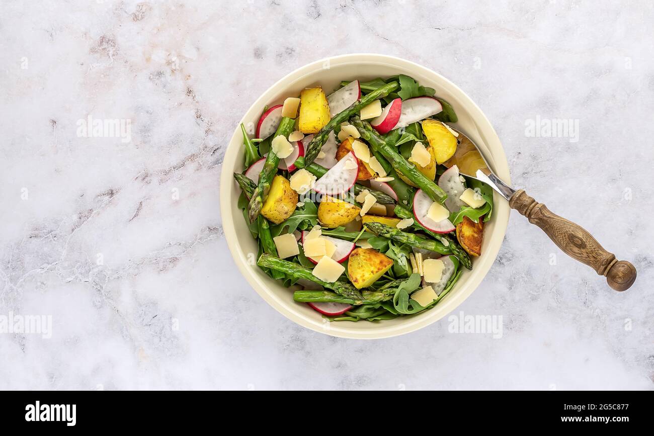 Grilled green asparagus salad with fresh radish, arugula, potatoes, and parmesan cheese.  Stock Photo