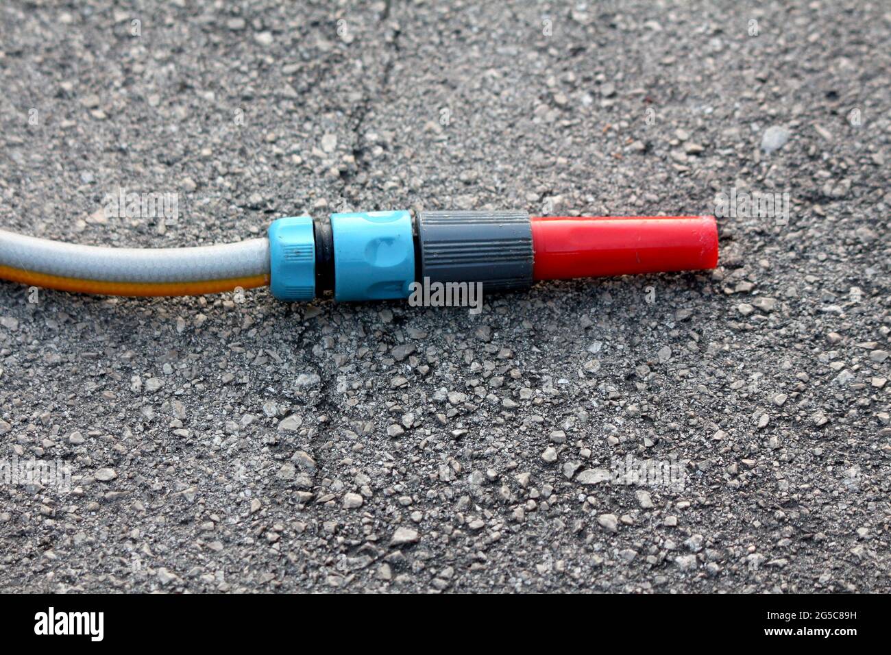 Plastic garden hose nozzle in various colors from red to grey and light  blue left in suburban family house paved driveway on warm sunny spring day  Stock Photo - Alamy