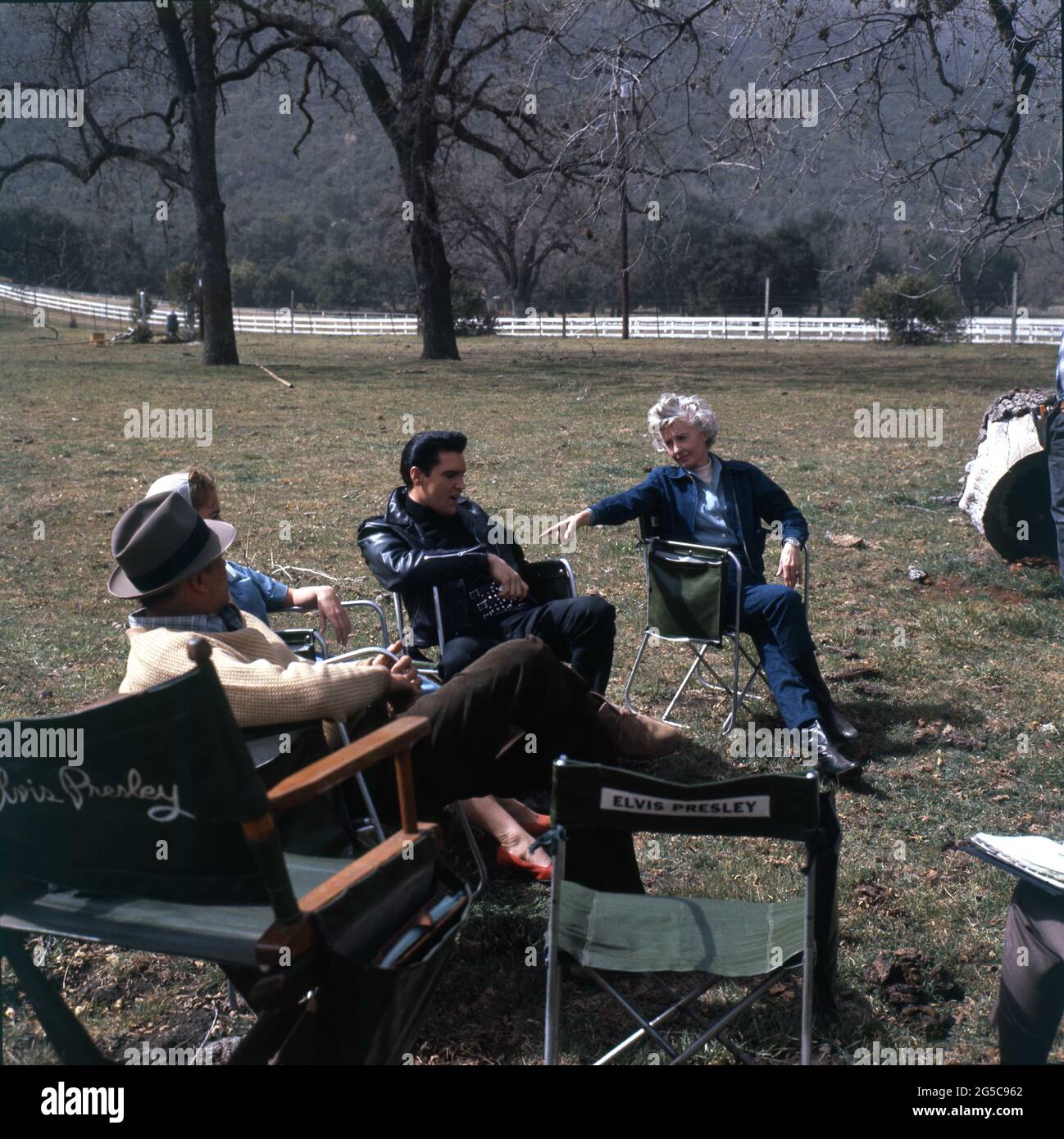 LEIF ERICKSON JOAN FREEMAN ELVIS PRESLEY and BARBARA STANWYCK going over their lines in script on set location candid during filming of ROUSTABOUT 1964 director JOHN RICH screenplay Anthony Lawrence and Allan Weiss cinematography Lucien Ballard costume design Edith Head Wallis-Hazen / Paramount Pictures Stock Photo