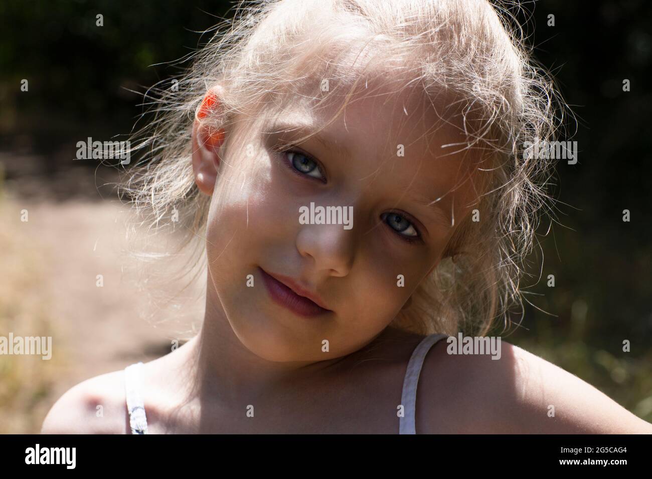 Caucasian blond girl with a cute smile looks sad. Close-up portrait Stock Photo