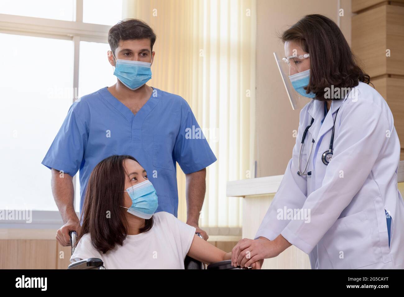 asian female doctor with male nurse wearing protective face mask reassured and consult young woman patient before surgery treatment at hospital. Stock Photo