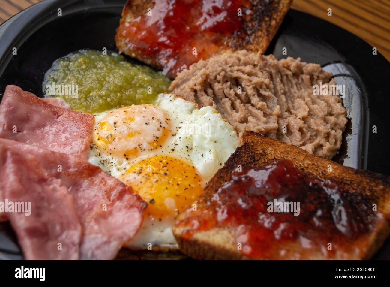 Photograph of a pair of fried eggs with beans, jam and bread with jam Stock Photo