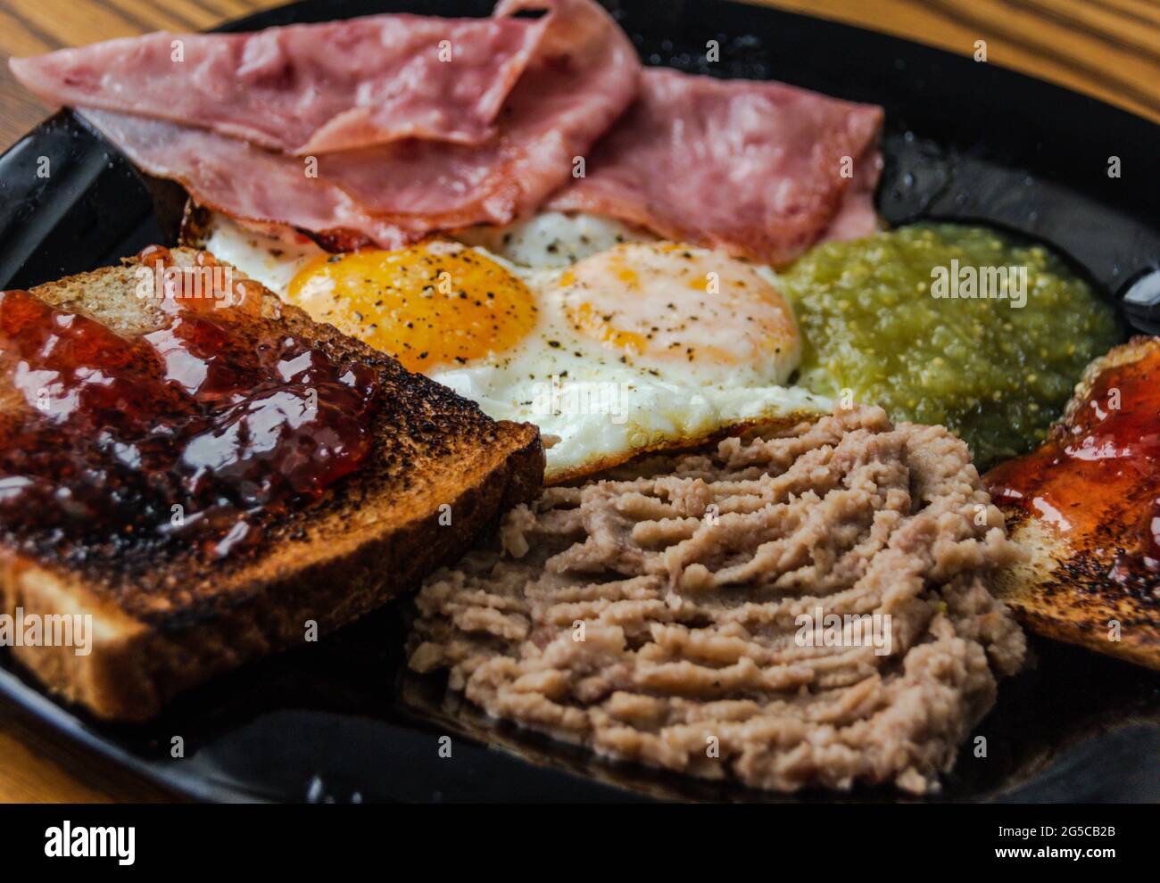 Photograph of a pair of fried eggs with beans, jam and bread with jam Stock Photo