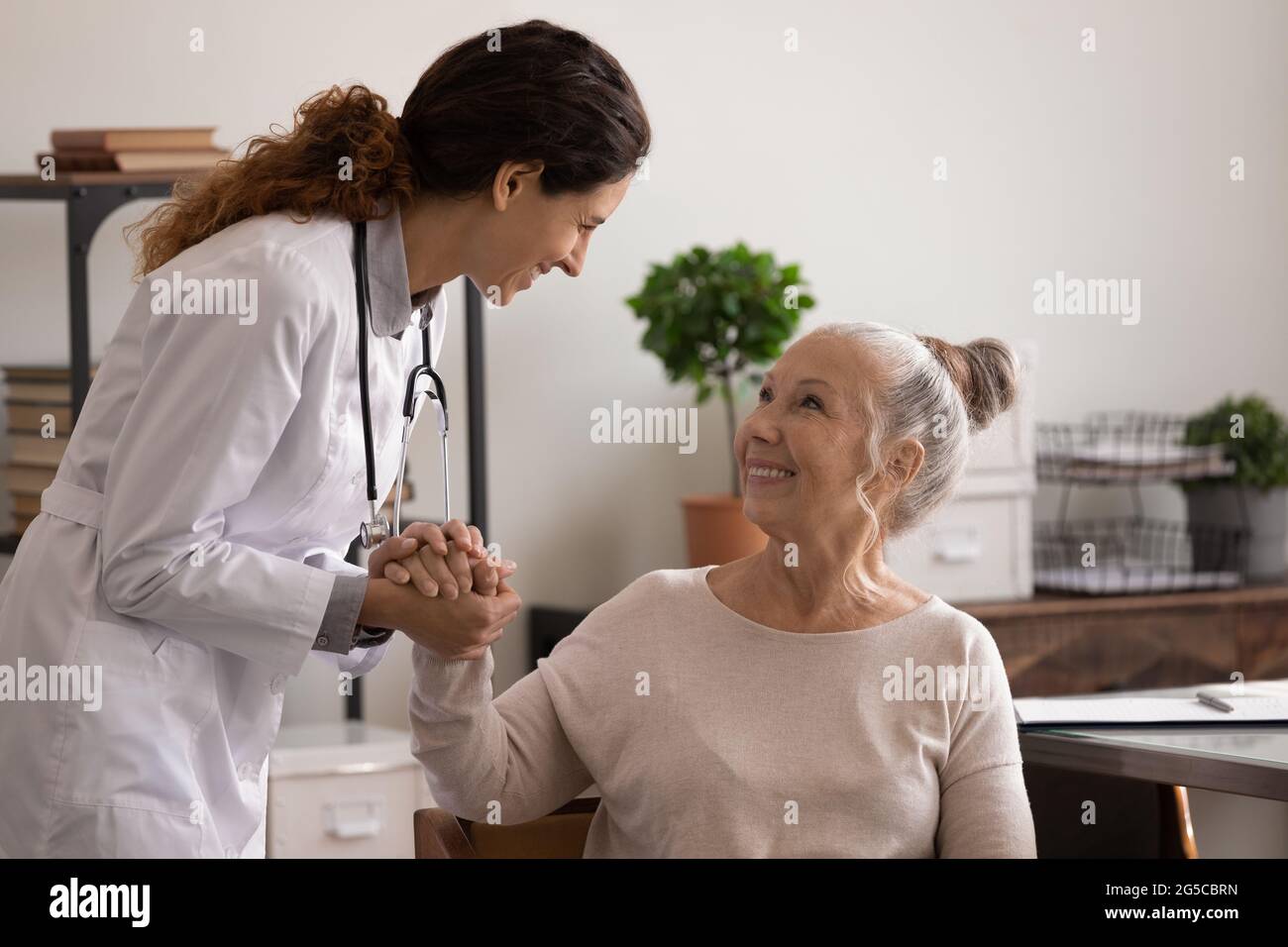 Smiling nurse comfort old female patient in hospital Stock Photo