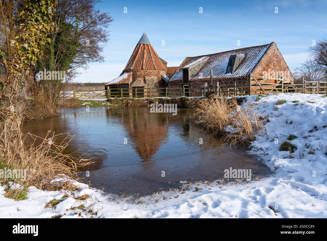 Historic Preston Mill seen in the snow on a bitterly cold sunny day in East Linton, East Lothian, Scotland, UK Stock Photo