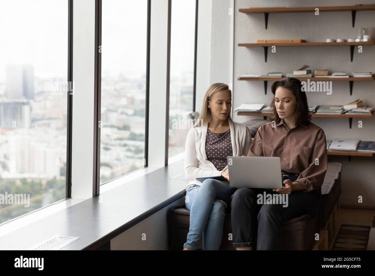 Focused two female colleagues working on computer in modern office. Stock Photo