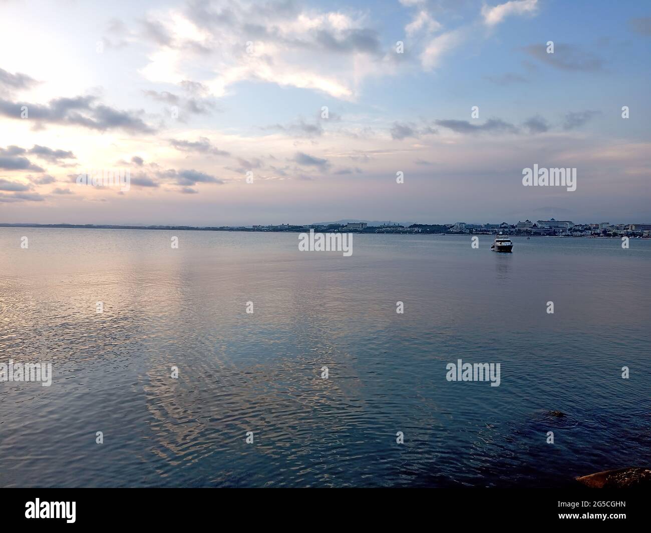 Sea with boats and the reflection of the cloudy sky Stock Photo - Alamy