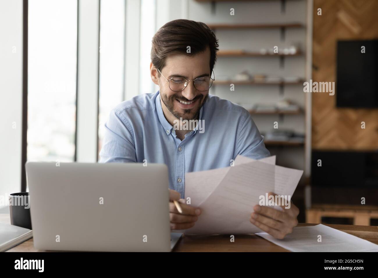 Happy young successful businessman analyzing paper documents. Stock Photo