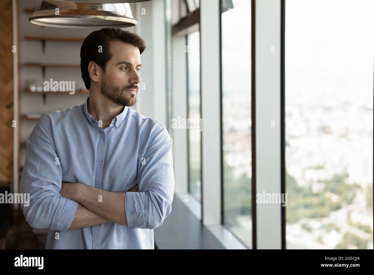 Confident pensive young man looking out of window. Stock Photo