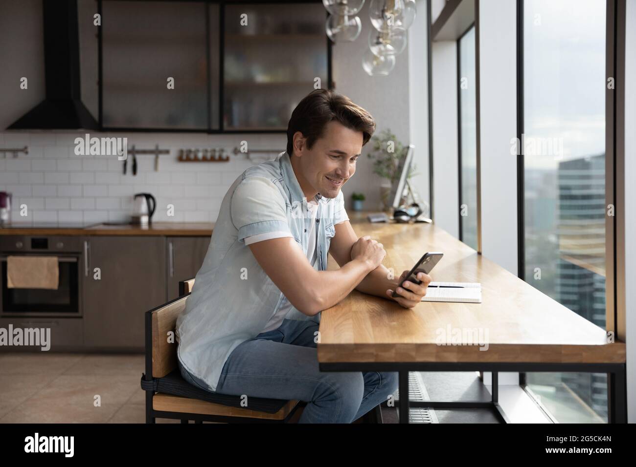 Happy young handsome man using smartphone in office kitchen. Stock Photo