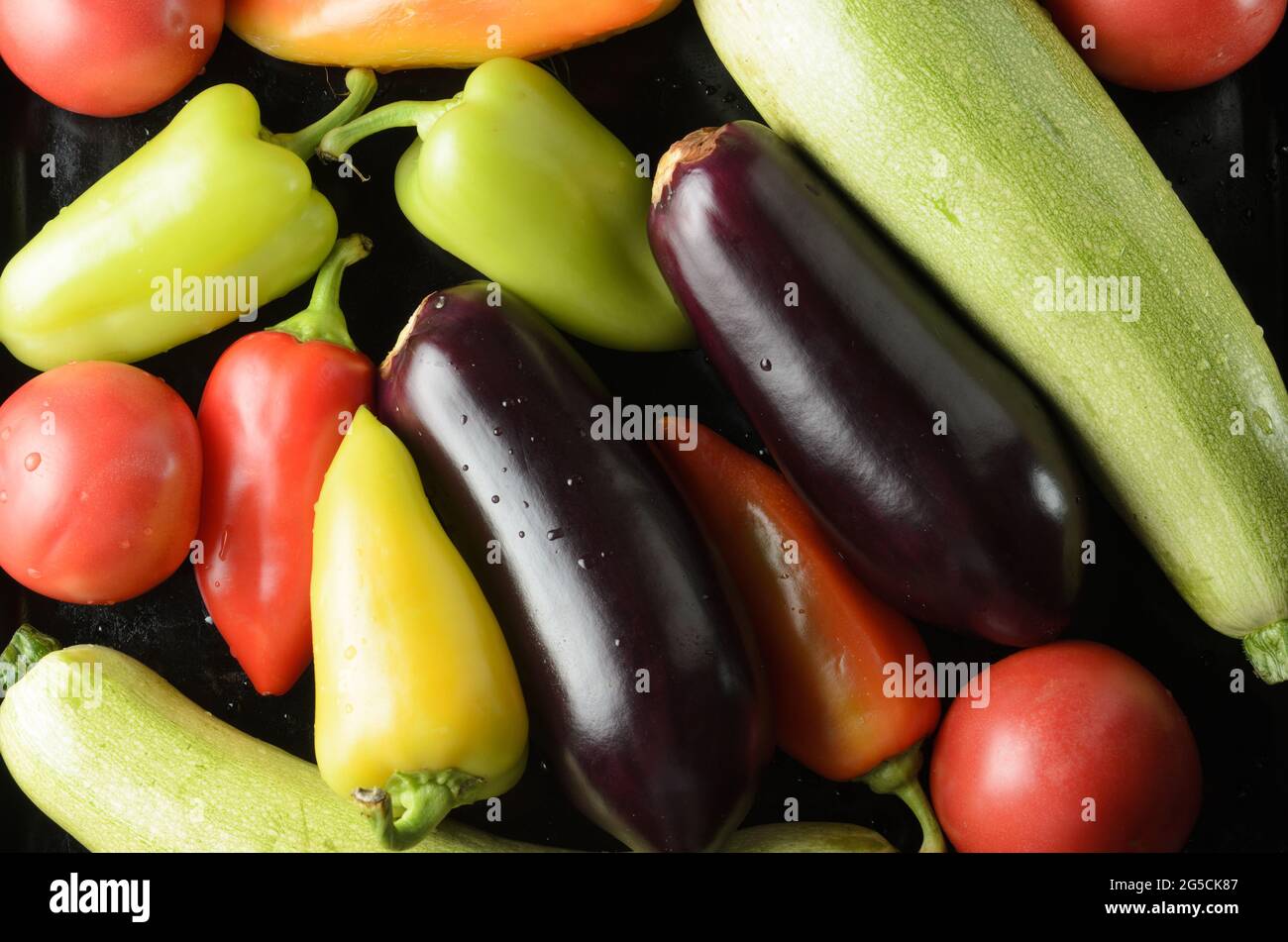 Bell peppers, tomatoes, zucchini, vegetables spread out on a black