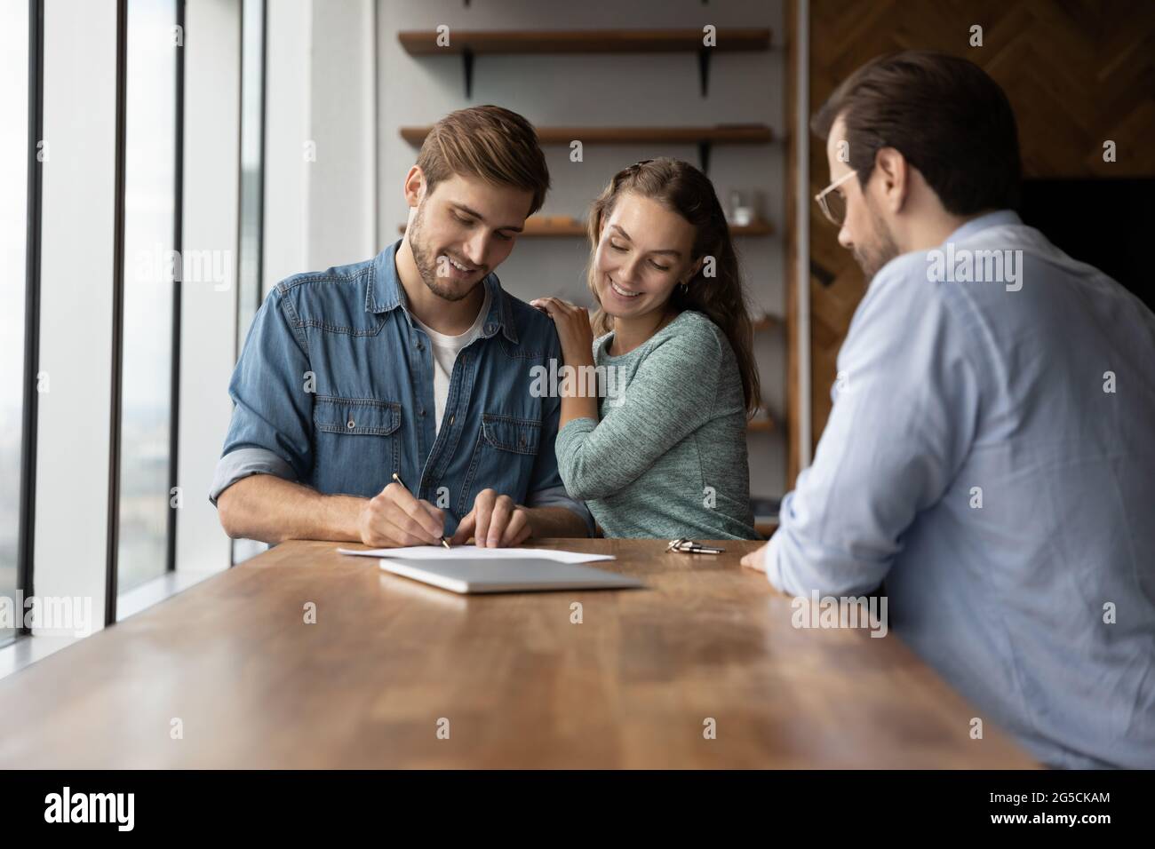 Loving young happy couple signing agreement document. Stock Photo