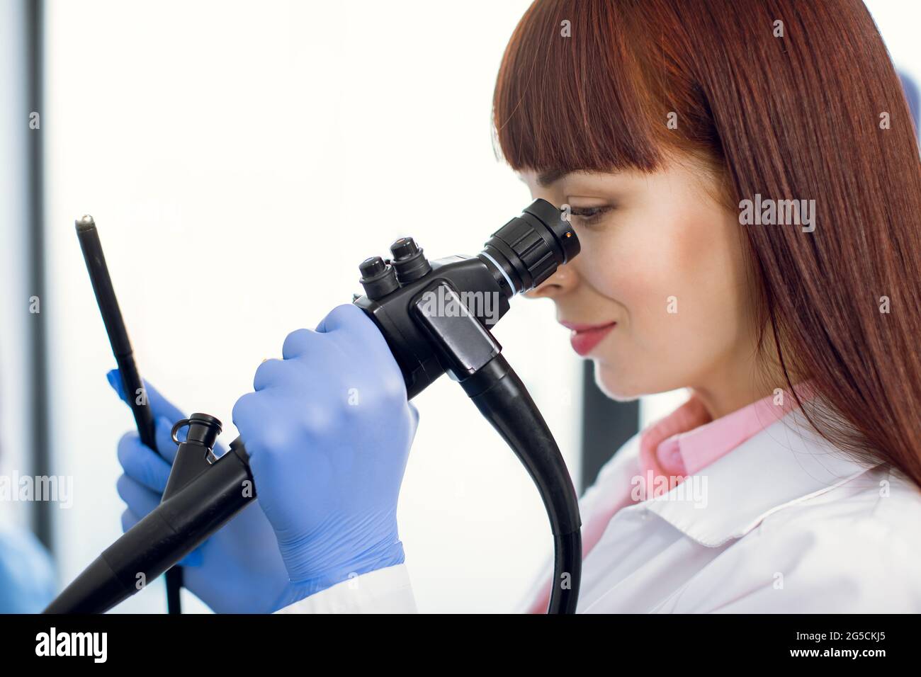 Instrument for endoscopy in the hands of pretty young Caucasian female doctor, performing gastrointestinal fiberoptic endoscopy. Close up portrait. Stock Photo