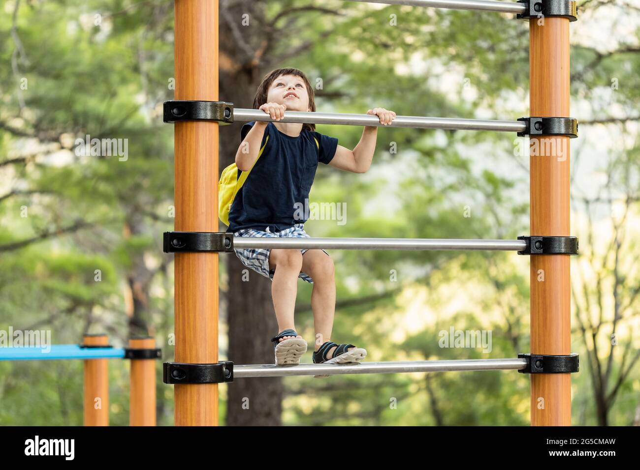 A young child climbing on athletic ladder at a playground Stock Photo