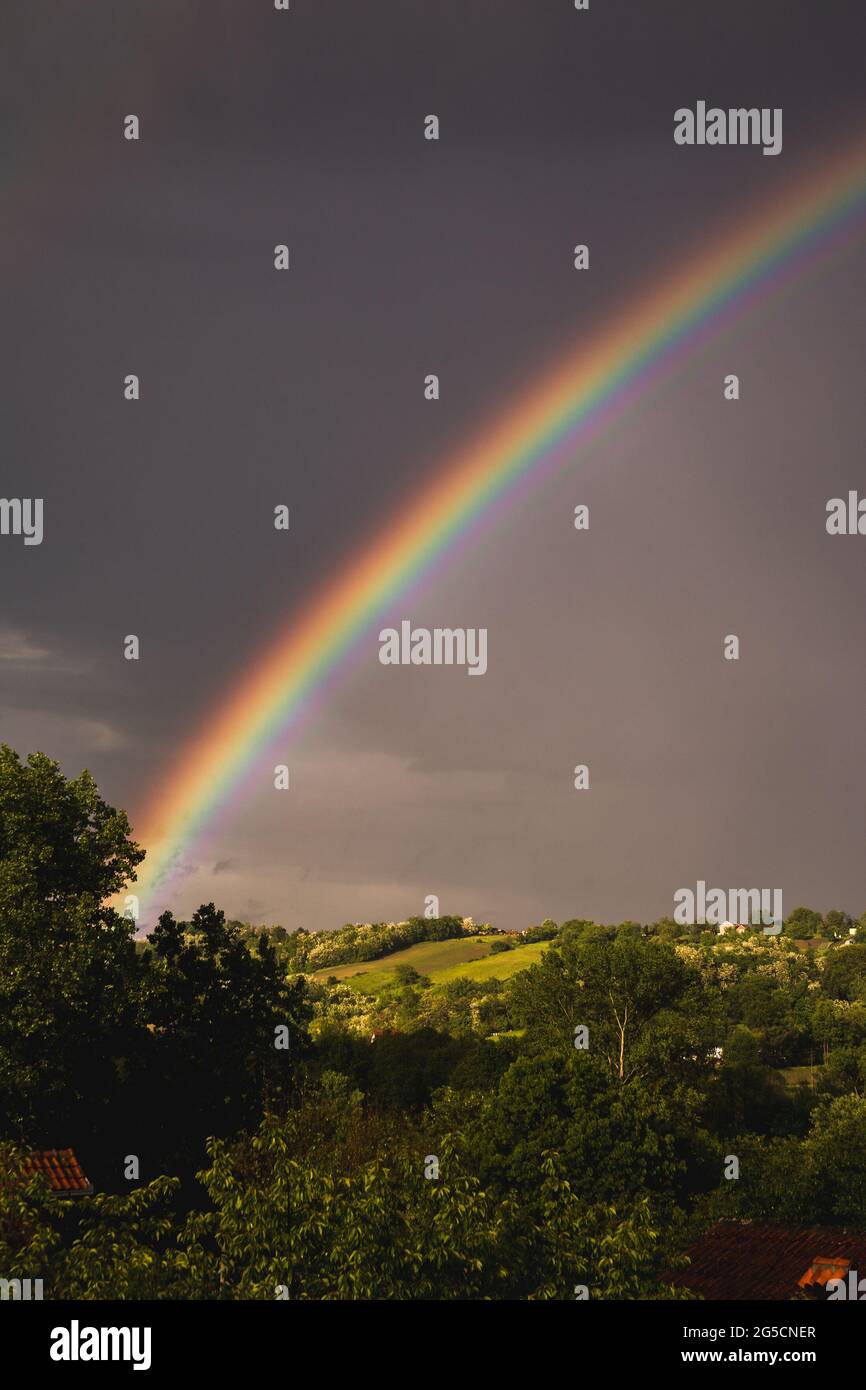 Beautiful view of a rainbow in the gloomy sky after the rain over the ...