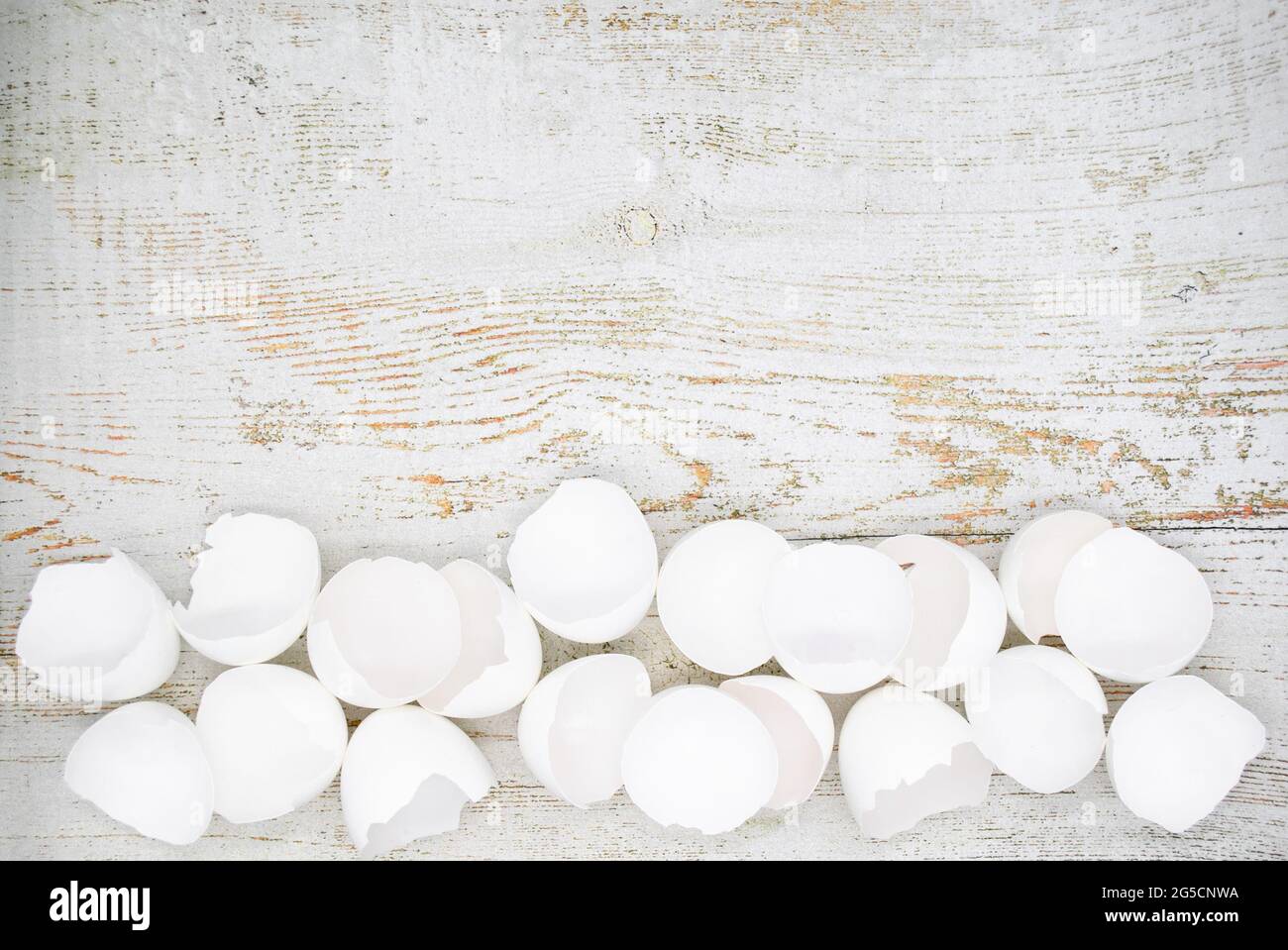 Lots of broken white eggshells on a light wooden background. Copy space. Stock Photo