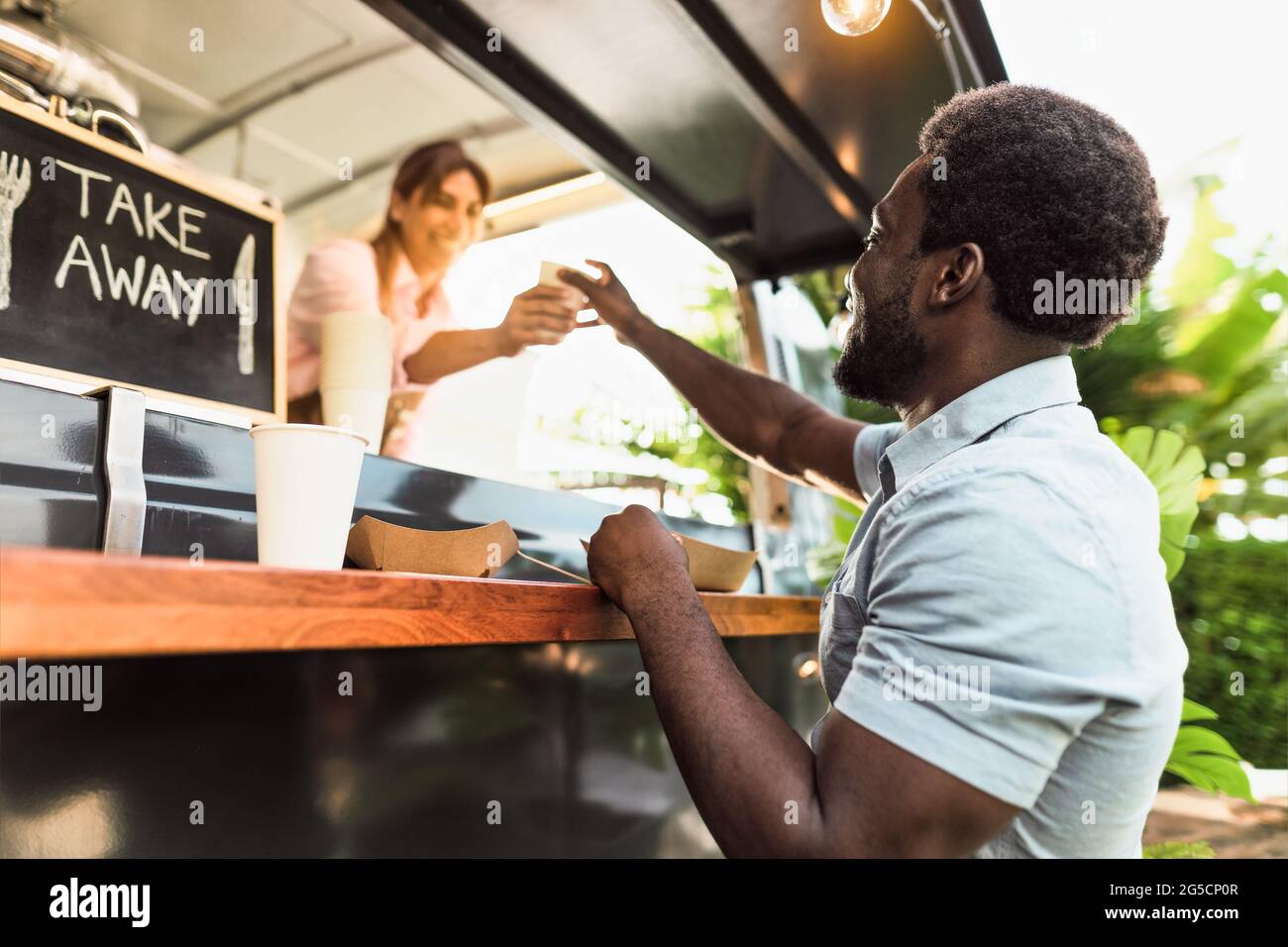 Young African man buying meal from food truck - Modern business and take away concept Stock Photo