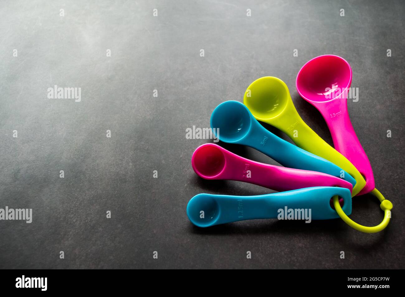 Multicolor empty measuring spoons of different sizes on a black