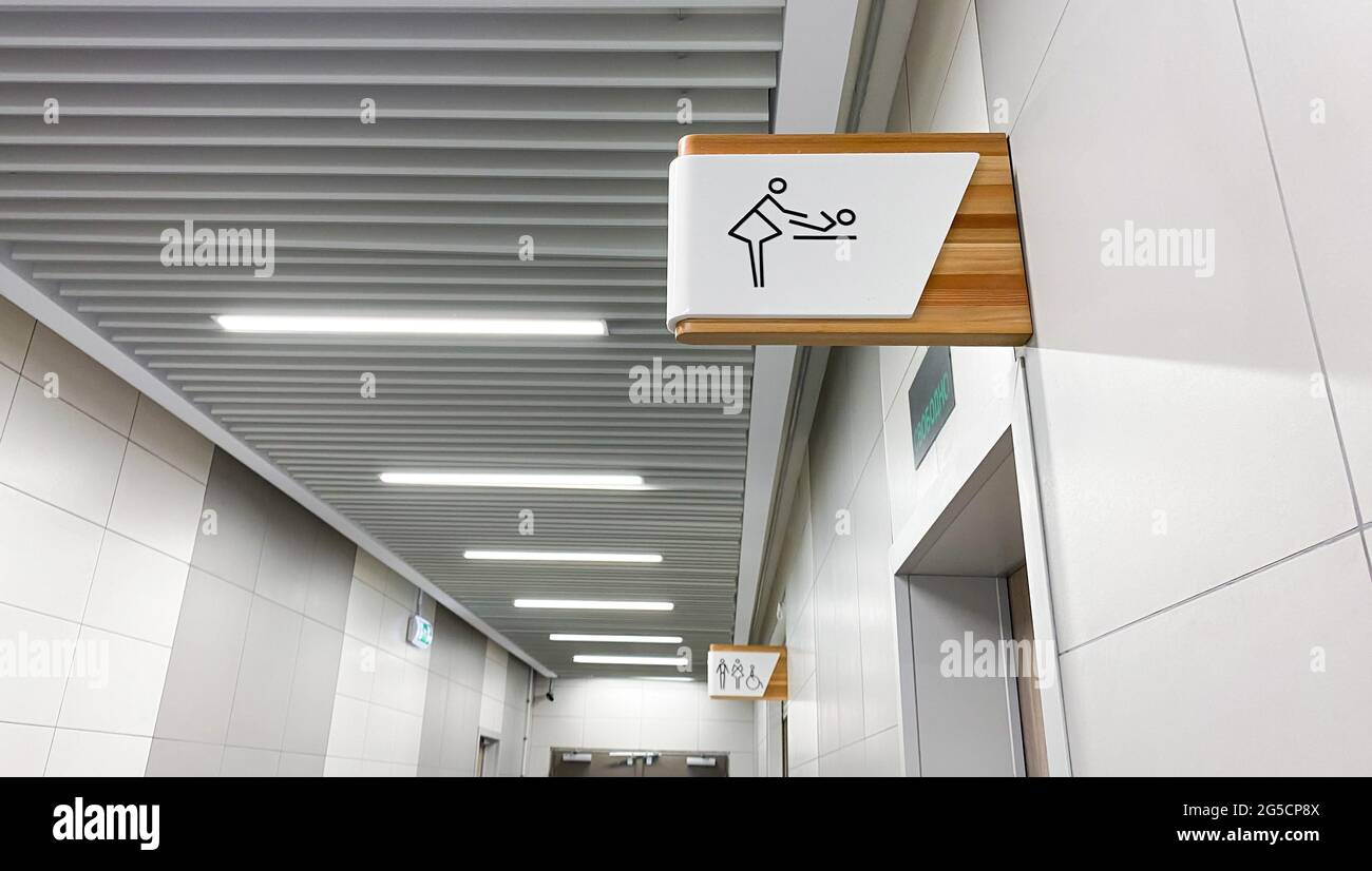 Public toilet sign for restroom. Baby changing facilities and feeding area. Men, women and disabled lavatory on blurred background. Stock Photo