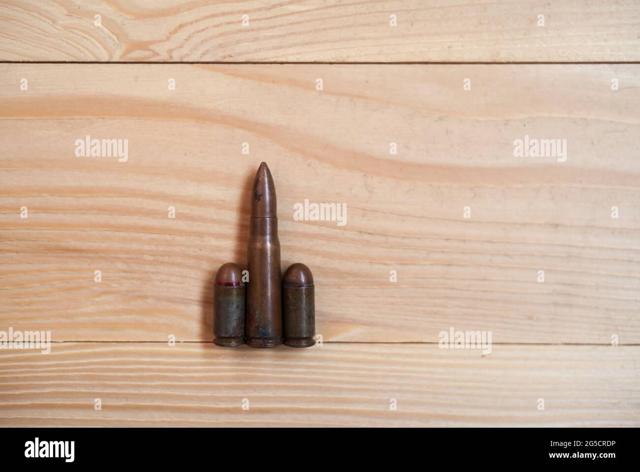 Bullets on a wooden background. Three different caliber bullets together on a wooden background. Military concept. Stock Photo