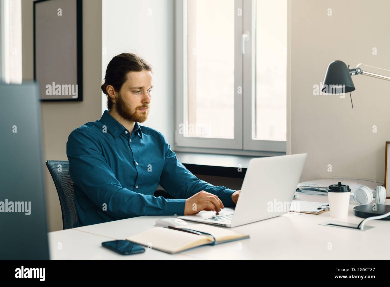 Young focused man freelancer working on laptop computer remotely Stock Photo