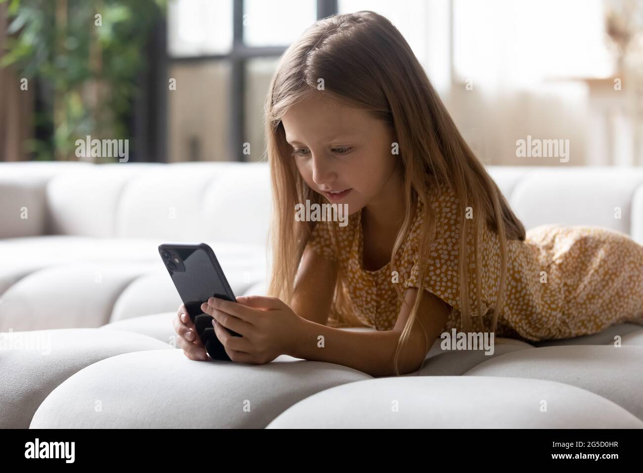 Addicted to modern tech small girl playing mobile games. Stock Photo