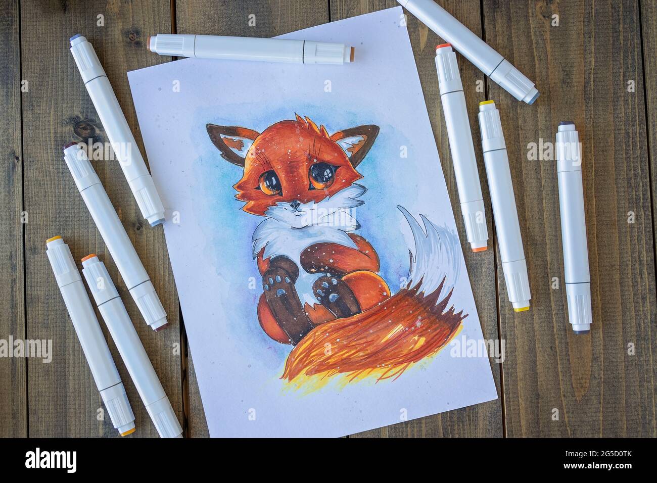 Flat lay with sketching ittle red-haired cute fox with a bushy tail. All placed on wooden table picture and markers. Hobby. Drawing fox. Top view. Soft focus Stock Photo