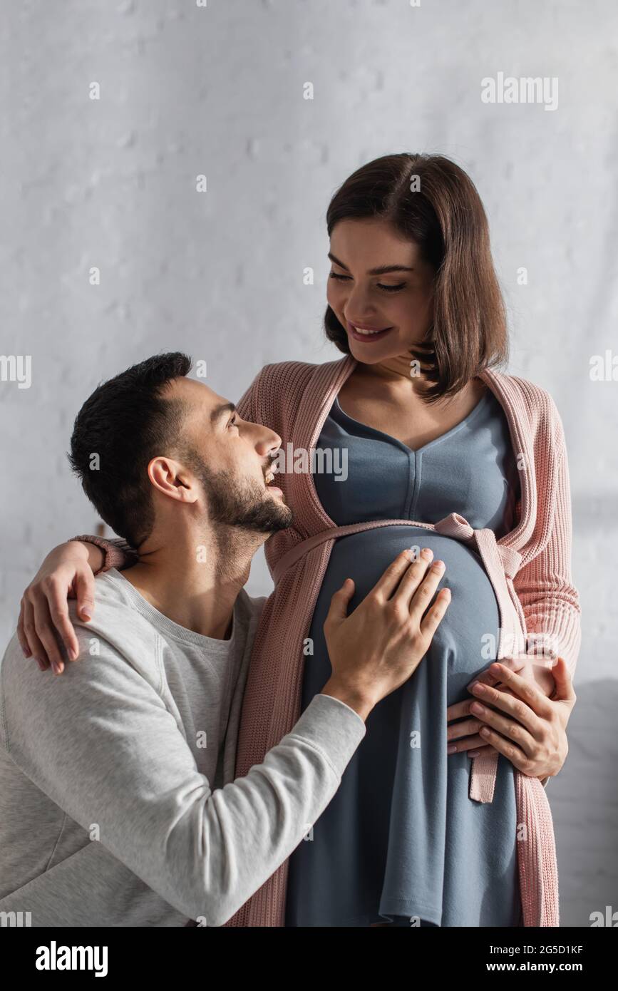 young man gently hugging belly of pregnant woman in kitchen Stock Photo ...