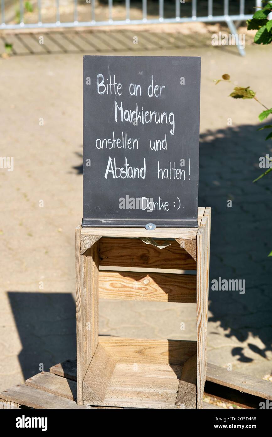 Sign in front of a restaurant in germany with the words Please line up at the marker and keep your distance Stock Photo