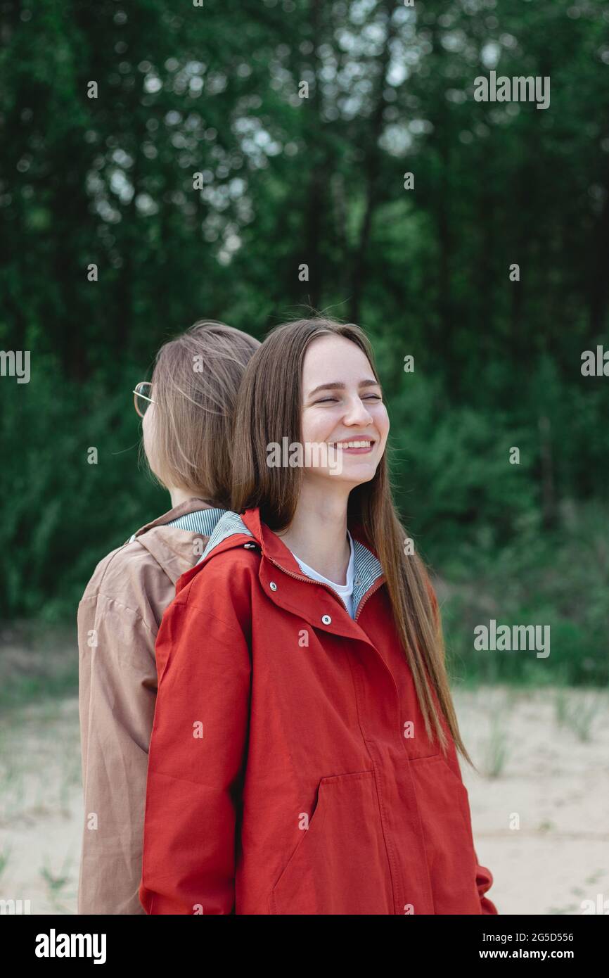 Two young caucasian young women friends standing back to back and ...