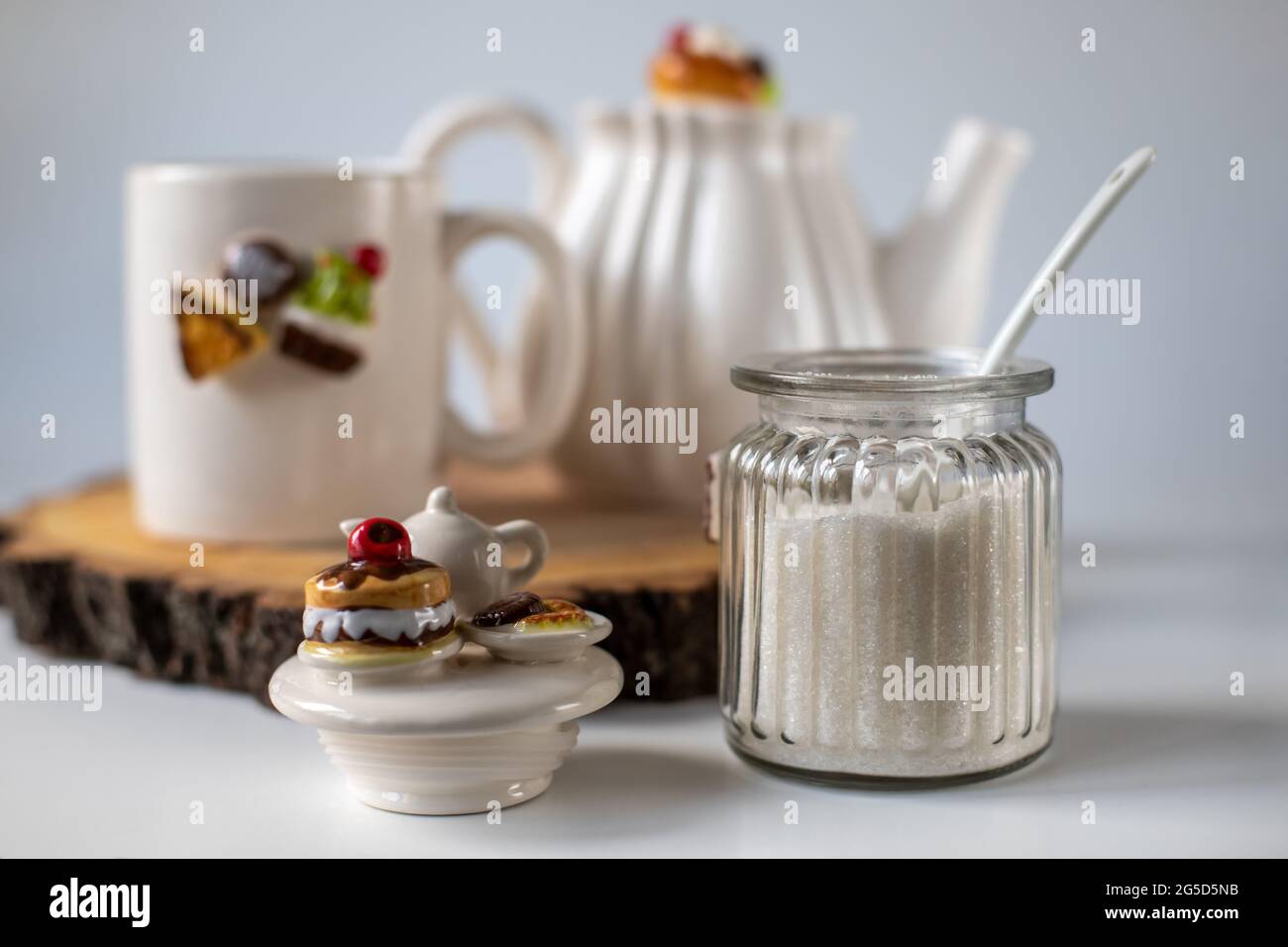 Sugar in a transparent jar. White utensils for tea drinking. The decor