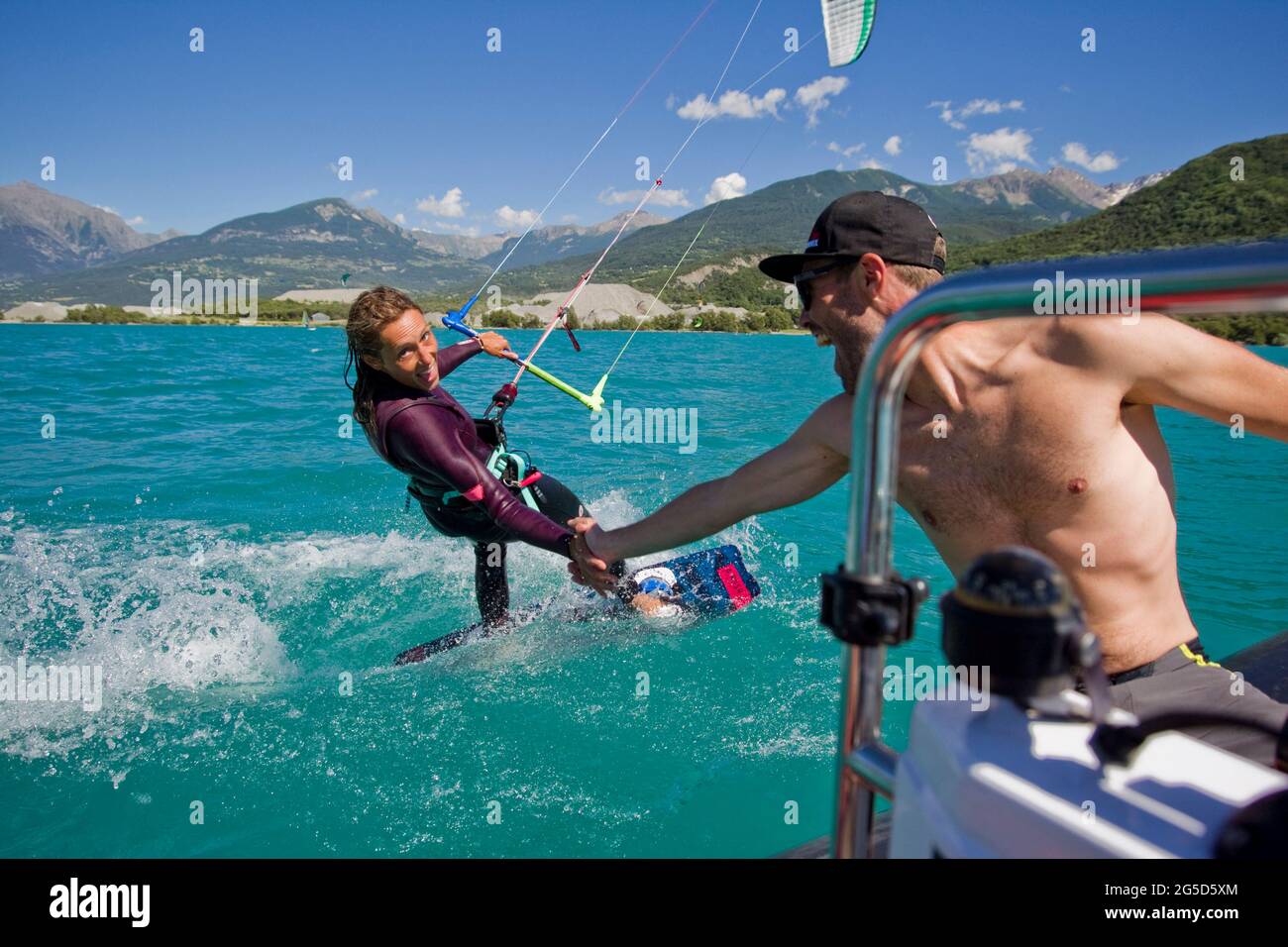 Le Lac, France. 26th June, 2021. A woman kitesurfing on Lac de Serre-Poncon here she claps the hand of a man who pilots a boat, Savine le Lac, Hautes Alpes, France on June 25, 2021. Photo by Durand Thibaut / ABACAPRESS.COM Credit: Abaca Press/Alamy Live News Stock Photo